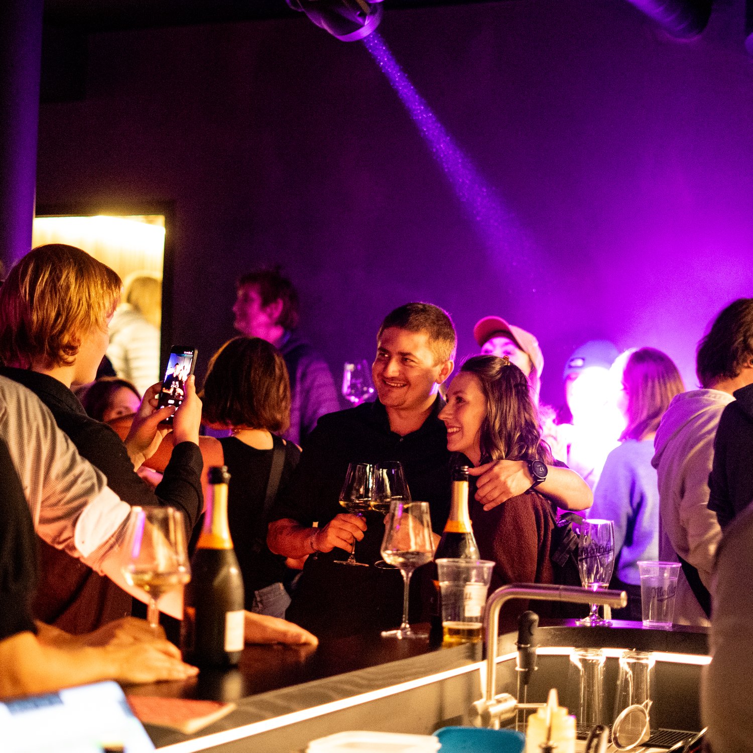 kellerbar-gaeste-anstossen-wein-lila-beleuchtung